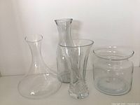 Four clear glass vases and pitchers together showing shape and relative size