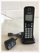 Panasonic cordless landline phone model PNLC1073 XA handset standing on its charging base with keypad visible and power cord attached.