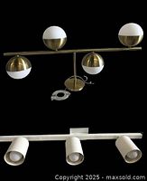 Linear vanity chandelier with 5 spherical opal glass and gold metal shades shown mounted on gold rod frame.