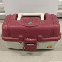 Closed red and white plastic fishing tackle box with handle and latch.