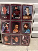 Close-up of nine Star Trek trading cards showing characters like Captain Picard, Commander Riker, Data, Troi, Worf, and others with red borders and Star Trek logo.