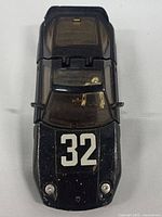 Top view of black Super Go Bots enemy sports car toy with white number 32 on the hood, showing windshield and body details.