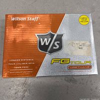 Front of boxed Wilson Staff FG Tour Urethane golf balls in new tour yellow color in factory sealed packaging.