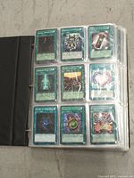 Front side view of trading cards in a binder sleeve, displaying 9 cards fitting in one plastic page, mostly spell cards visible