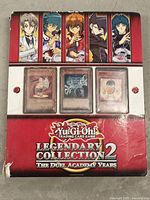 Front cover of the Yu-Gi-Oh Legendary Collection 2 binder showing characters and 3 example cards in protective sleeve.