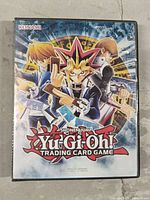 Front cover of a small binder featuring Yu-Gi-Oh characters and Konami branding.