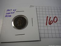Front view of 1907 US Indian Head Penny in a white paper flip holder with handwritten notation.