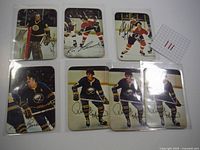 Seven 1977 O-Pee-Chee hockey cards laid out on white surface, showing color images and facsimile autographs