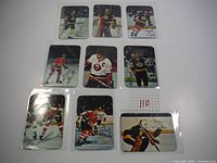Nine 1977 Topps glossy hockey cards arranged in rows, showing players in action poses with printed signatures.