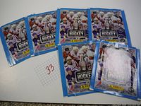 Six unopened packs with blue borders, various NHL player images, and Stanley Cup trophy graphic in the center. Each pack branded Panini NHL 2009-10 hockey rookie stickers.