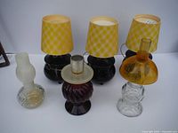 Six Avon lamp bottles displayed together, three with shades and three without.