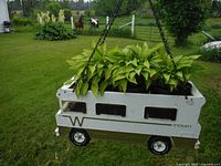Front side view of the hanging planter showing the leafy plants inside the Tonka Winnibego toy vehicle planter.