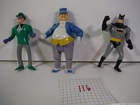 Front view of Batman, The Penguin, and The Riddler figures arranged side-by-side