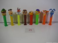 Full front view of 8 PEZ candy dispensers with character heads from various cartoon series, placed in line