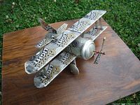 Front angled view of handmade Coors Light airplane model showing biplane wings, logo on wing surfaces, and propeller detail.