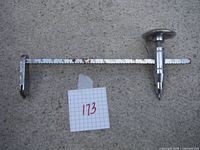 Full view of the adjustable glass circle cutter laying on a grey surface, showing the measuring arm and the cutting wheel end.
