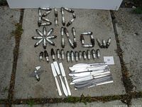 Photo showing spark plugs arranged to spell letters and shapes with knives and forks laid nearby