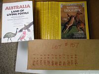 Photo showing a large number of yellow National Geographic magazines stacked upright with two on display including one with kangaroo on cover and the other being the Australia Land of Living Fossils booklet.