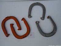 Four horseshoes, two orange and two silver, arranged on a white surface