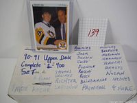 Photo showing box of hockey cards with a single encased Jaromir Jagr rookie card propped against it and a handwritten list of rookie names and set completion details.