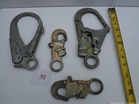 Four metal double locking carabiners of different sizes displayed with measuring tape for scale.