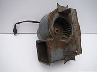 Front angle view showing squirrel cage fan inside rusted metal housing and attached power cord.