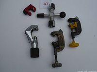 Overview of five tubing cutters of various sizes and conditions, two with yellow knobs, one chrome-plated with black grip, one small red plastic cutter.