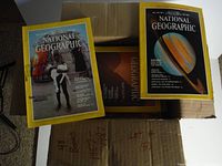 Shot showing multiple National Geographic magazines with typical yellow borders in a cardboard box. Visible issues include a 1957 and others.