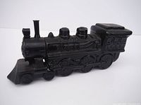 Side angle view of the black glass Avon locomotive decanter showing details of the train body and wheels.