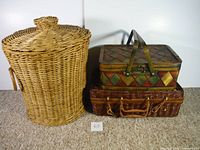 Three wicker baskets grouped together on carpeted floor: a large round lidded basket, a small rectangular wicker basket with latch, and a colorful patterned rectangular basket.