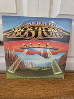 Front cover of Boston 'Don't Look Back' vinyl LP showing flying saucer and cityscape graphics with band name.