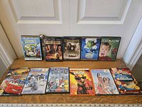 Eleven children's and family movie DVDs laid out, cases visible showing titles and artwork.