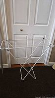 Front view of the white folding laundry rack in open position, showing structure and size.