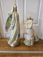Both ceramic garden angel statues, left with painted wings and floral details, right with butterfly decorations and missing wings