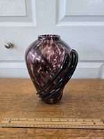 Front angled view of the purple and white art glass vase with raised black glass ribbons, showing size with ruler beneath.