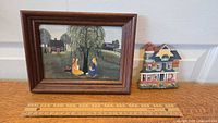 Framed print with rural scene by Lucy Ogletree and ceramic house key holder on flat surface with measuring ruler for scale.