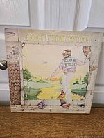 Front cover of the album showing illustrated man and yellow brick road landscape