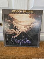 Front cover of "Running On Empty" album featuring a road, cloudy sky, and drum set artwork