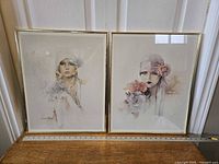 Photo of two framed lithograph prints by Sara Moon placed side by side on a surface with a ruler measuring the width.