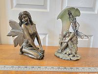 Two fairy sculptures together, one painted figure with repaired wings, one bronze fantasy vase with fairy figure