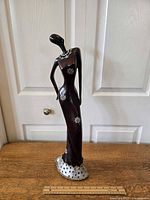 Front view of 22.5 inch resin African lady figure on wood surface against light door background.