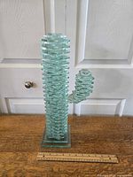 Front view of stacked glass cactus sculpture with a wooden ruler in front showing size.