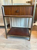 Front view of the side table showing the drawer and lower shelf with bronze metal frame