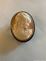 Front view of oval cameo pendant and brooch showing the carved woman’s profile and silver mount