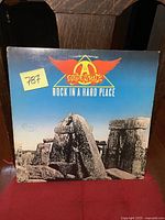 Front cover of Aerosmith Rock in a Hard Place vinyl LP showing Stonehenge and band logo with minor wear and a small sticker.