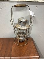 Front view of the antique CPR kerosene lantern showing metal body, wire cage, glass globe, and wooden handle with rust and wear.