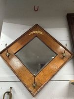 Full view of antique hall rack diamond shaped mirror with oak frame and brass hooks