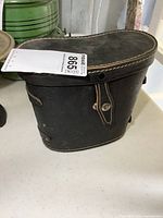 Closed black leather carrying case with snap closure, visible stitching, and compact size for carrying binoculars.