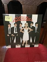 Front cover of Blondie Parallel Lines vinyl record album showing band in black suits and white dress on striped background.