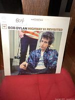 Front of Bob Dylan Highway 61 Revisited vintage LP album cover featuring a color photo of Bob Dylan sitting wearing a patterned jacket and holding a cigarette, with an orange '804' marking handwritten at top left corner.